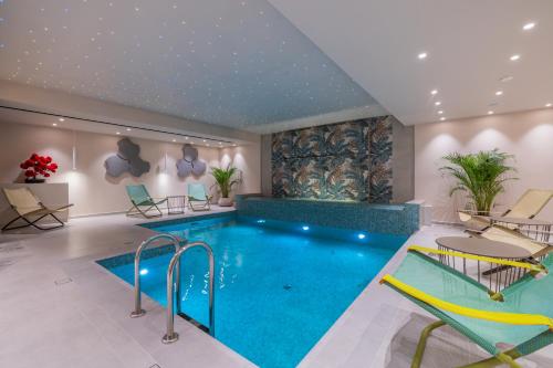 a pool in a room with chairs and a couch at Ionian Plaza Hotel & Spa in Argostoli