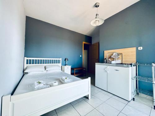 a bedroom with a white bed and a blue wall at Ktima Holoway Apartments in Therma
