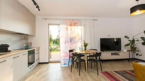 a kitchen with a table with chairs and a television at Dom Gościnny 2 Ogrodowa in Wiślinka