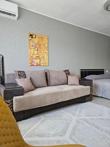 een woonkamer met een bank en een bed bij Квартира-студия рядом с Набережной in Balqash