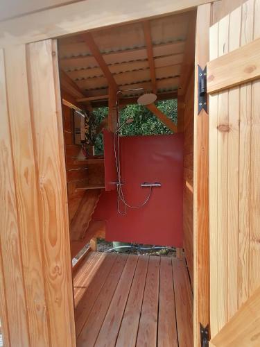 une porte ouverte d'une petite maison avec un mur rouge dans l'établissement Yourte Mongole Aux nuits insolites d'Argoumbat, à Beaumont-de-Lomagne