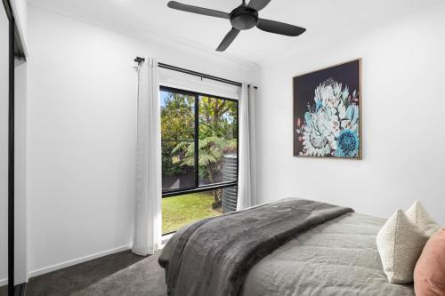 a bedroom with a ceiling fan and a window at Secluded Luxury 2BR Rainforest Retreat Free Wi-Fi in Springbrook