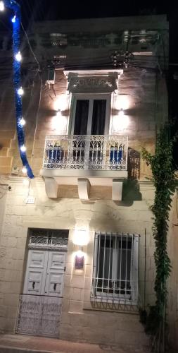 a building with a white balcony and a window at The Anchor Townhouse in St Paul's Bay