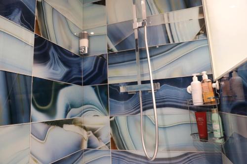 une salle de bain avec douche aux carreaux bleus et blancs dans l'établissement Surfin You Essaye, à Biarritz