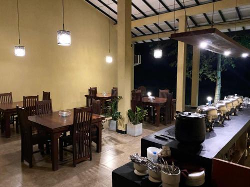 a restaurant with wooden tables and chairs and a bar at Athyantha Resort in Anuradhapura