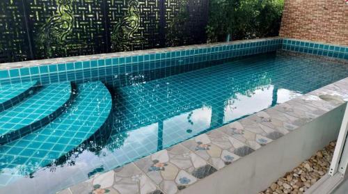 a swimming pool with blue tiles on the ground at ปูณิสาวิลล่าPoonisavilla in Ban Khlong Kao (6)