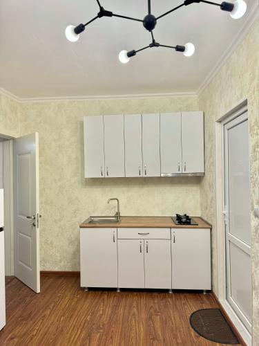 an empty kitchen with white cabinets and a ceiling at Evergreen Surami Hotel in Surami