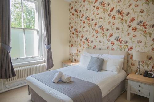 a bedroom with a bed with a flowery wallpaper at Woodland Manor Hotel in Bedford