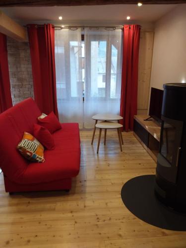 a living room with a red couch and a table at Appartement dans maison de village in Crots
