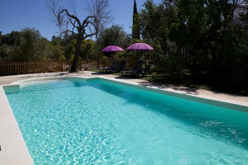 a swimming pool with two umbrellas in a yard at Amazing apartment, Olhao with pool, beach close by in Olhão