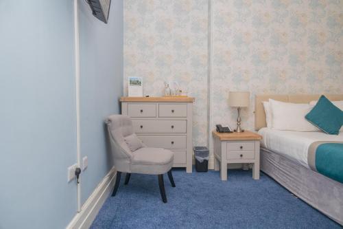 a bedroom with a bed and a chair and a dresser at Woodland Manor Hotel in Bedford