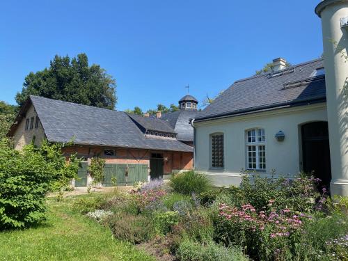 an old white house with a garden in front of it at Kleines Schloss Lanke in Wandlitz
