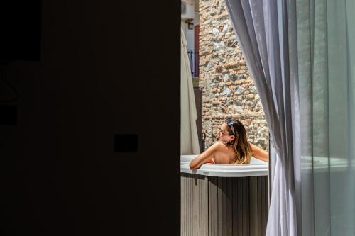 a woman sitting in a bath tub looking out a window at MARINO WELLNESS in Ali Terme