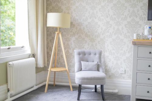 a chair and a lamp in a room at Woodland Manor Hotel in Bedford