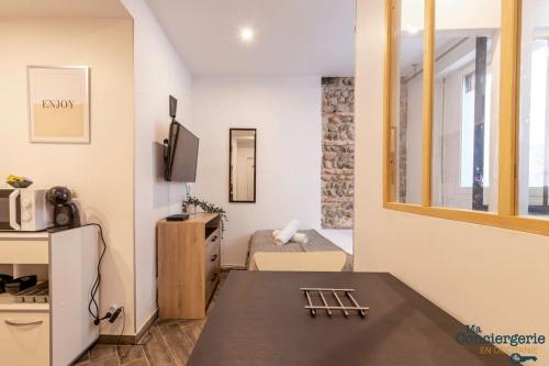 Elle comprend un petit salon avec une table et une télévision. dans l'établissement Moderne - Centre - Gare matabiau, à Toulouse