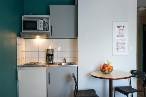 a small kitchen with a refrigerator and a table at Terres de France Brest in Brest
