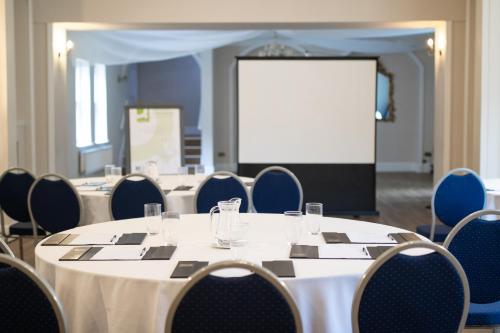 a conference room with a table and chairs and a screen at Woodland Manor Hotel in Bedford