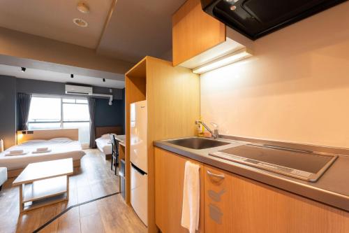 a kitchen with a sink and a room with a bed at e-stay namba in Osaka