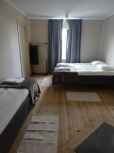 a bedroom with two beds and a wooden floor at Kungsgården BnB in Kungsgården