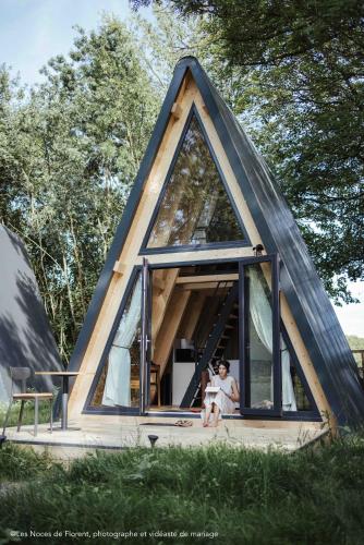 une maison triangulaire avec deux personnes assises devant elle dans l'établissement Ecolodges de rêve dans un château de conte de fées, à Les-Trois-Moutiers