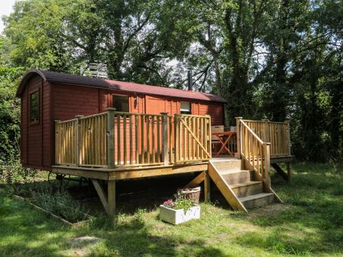 a small wooden cabin with stairs and a deck at The Foxes Den Shepherds Hut in Bristol