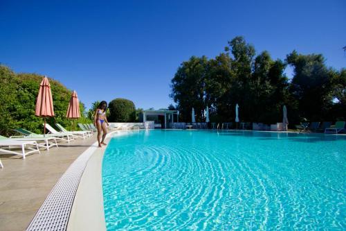a woman is standing next to a swimming pool at Eden Park Hotel in Marina di Campo