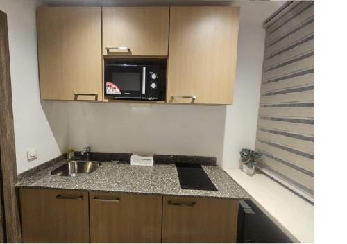 a small kitchen with a sink and a microwave at Bark Luxury Appartments @Signal Abidjan Plateau in Abidjan