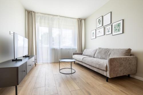 a living room with a couch and a television at ᴄᴏʜᴏsᴛ I 2BD Apartment With Balcony in Mažeikiai