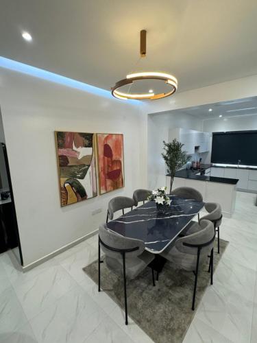 Harmony Spring Homes في إيكيجا: غرفة طعام مع طاولة وكراسي وتلفزيون