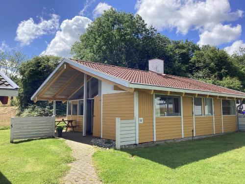 a small yellow house with a table in a yard at 5 person holiday home in Aabenraa-By Traum in Aabenraa