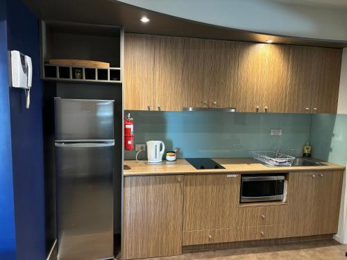 a kitchen with a stainless steel refrigerator and wooden cabinets at Waterfront@Waves in Cowes