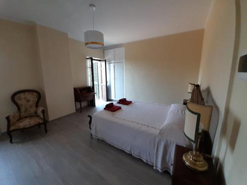 a bedroom with a white bed and a chair at Villa Pona in San Salvatore Monferrato