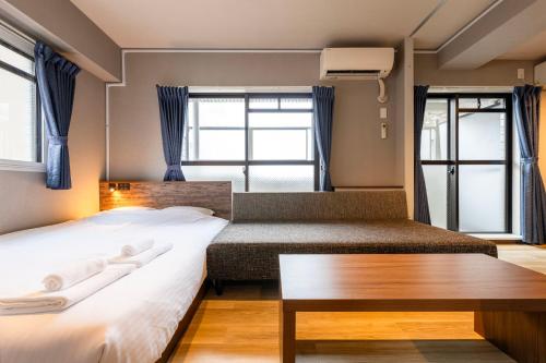 a hotel room with two beds and a bench at e-stay namba in Osaka