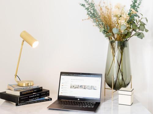 a laptop computer sitting on a table next to a vase of flowers at Pass the Keys Modern High End 1 Bed in Central Leamington Spa in Leamington Spa