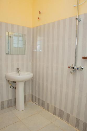 Un baño con un lavabo blanco y un espejo. en Legacy Homes, en Mutomo
