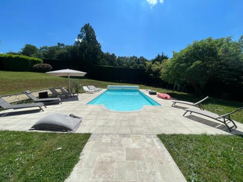 une piscine avec deux chaises et un parasol dans l'établissement Propriété*Piscine*Sarlat, à Sarlat-la-Canéda