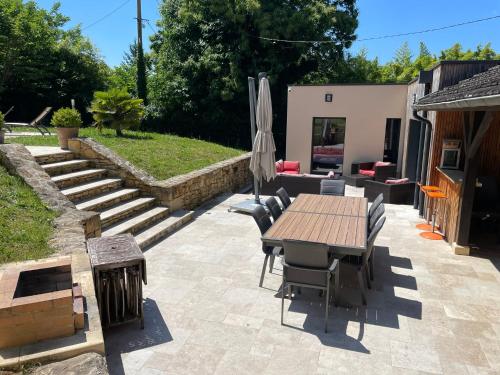 un patio avec une table, des chaises et un parasol dans l'établissement Propriété*Piscine*Sarlat, à Sarlat-la-Canéda