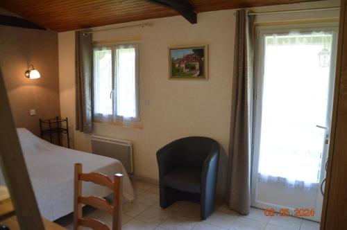 a bedroom with a bed and a chair and a window at Le chalet des Contries in Sarlat-la-Canéda