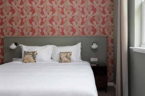 a bedroom with a large bed with a red wall at SCHLOSS Roxburghe, part of Destination by Hyatt in Kelso
