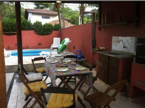 un patio con tavolo e sedie e una piscina di Linda Casa em Boiçucanga - São Sebastião, 4 suítes a São Sebastião