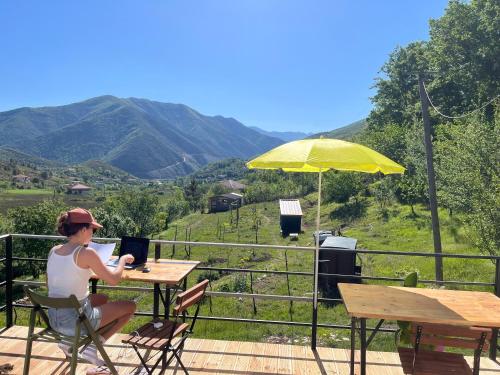 una donna seduta a un tavolo con un ombrello di Villa Lugina a Fushë-Buall