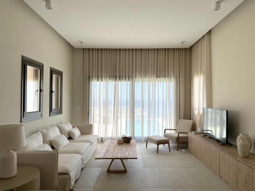 a living room with a white couch and a tv at Blue Gem Villa in Liaropá