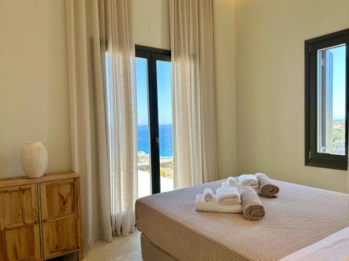 a bedroom with towels on a bed with a window at Blue Gem Villa in Liaropá