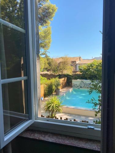 une fenêtre ouverte avec vue sur la piscine dans l'établissement Maison d'hôtes de charme 