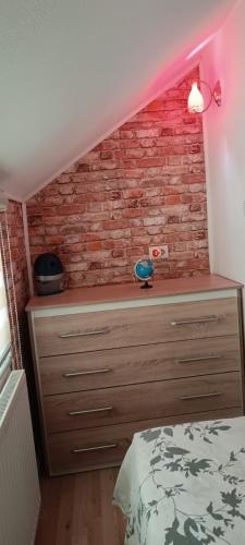 a bedroom with a bed and a brick wall at Apartman Denis Una in Lužine