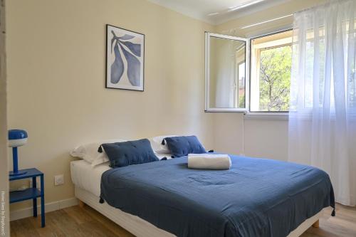 une chambre avec un lit avec des draps bleus et une fenêtre dans l'établissement Marseille Centre - Appartement 3 Chambres avec Balcon, à Marseille