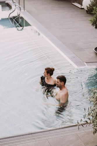 a man and a woman in a swimming pool at Hotel St. Florian in Frauenau