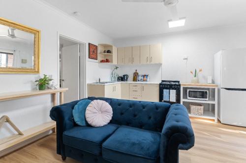 a living room with a blue couch and a kitchen at Botanical Bliss in Edge Hill