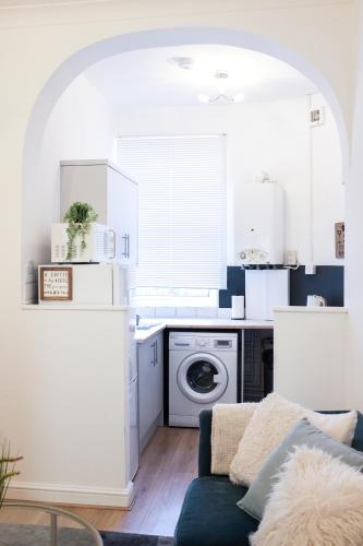 a kitchen with white cabinets and a blue couch at Portsmouth Apartment *Newly refurbished *Central in Portsmouth