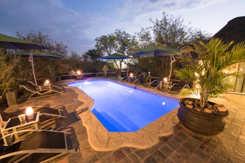 a swimming pool with chairs and umbrellas in a resort at African Rock Lodge in Hoedspruit